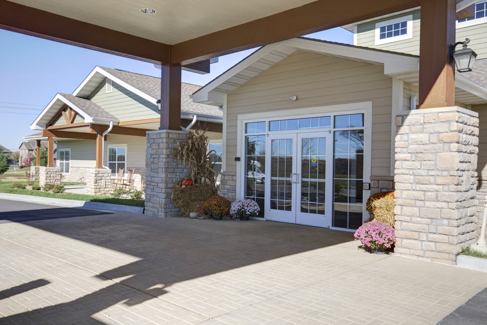 The entrance of a modern building featuring glass doors and landscaping.