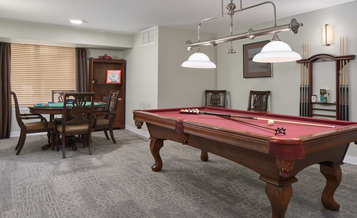 A recreation room featuring a pool table, chairs, and a lighting fixture.