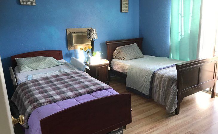 A cozy bedroom with two beds and blue walls.