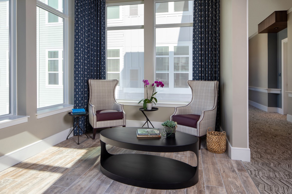 A cozy living room corner featuring two patterned chairs and a round coffee table with an orchid centerpiece.