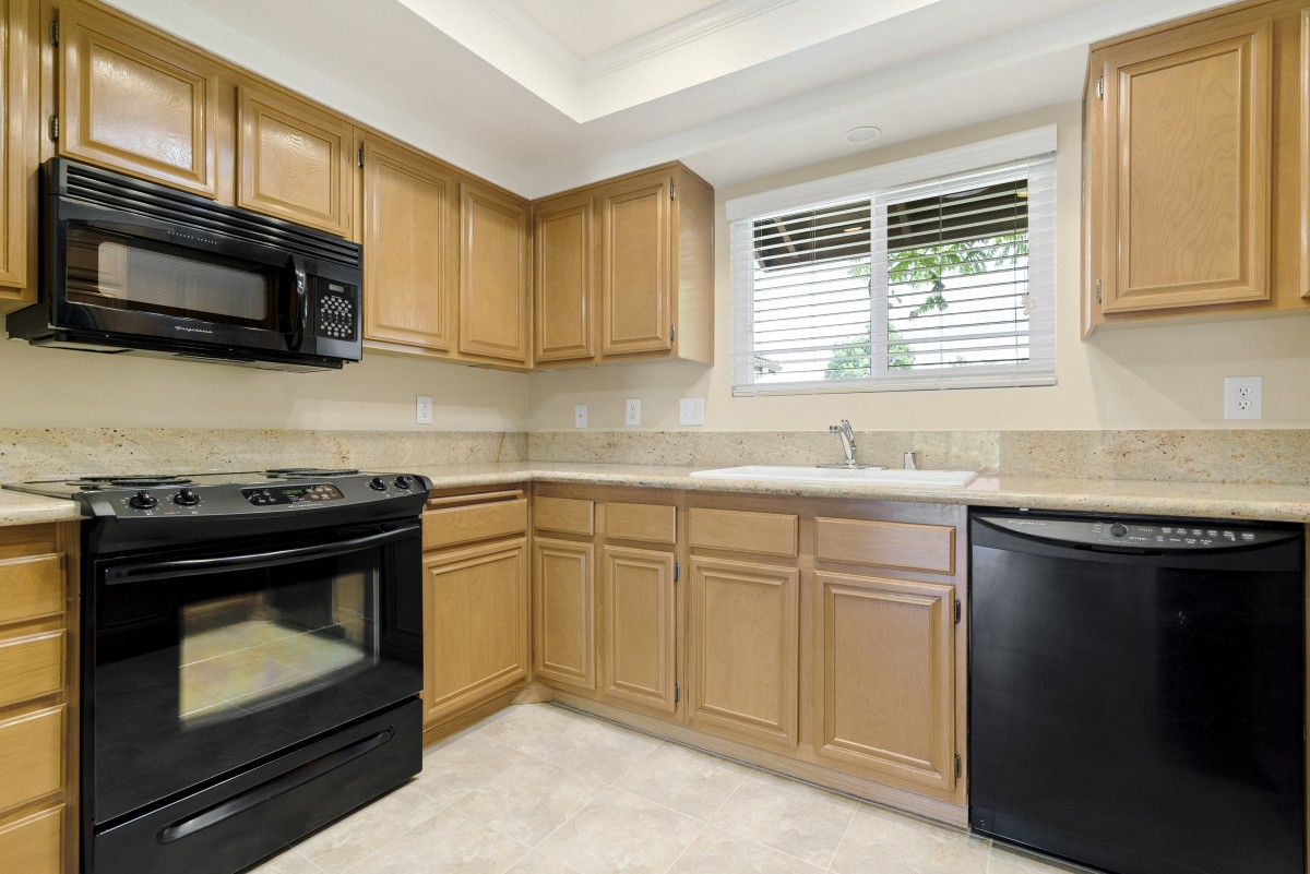 A modern kitchen with wooden cabinets and black appliances.
