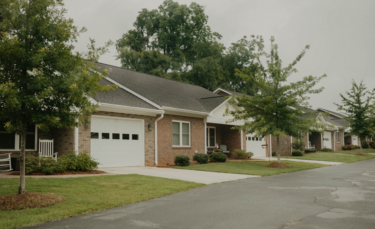 A suburban house with a driveway and garage, surrounded by trees and grass.