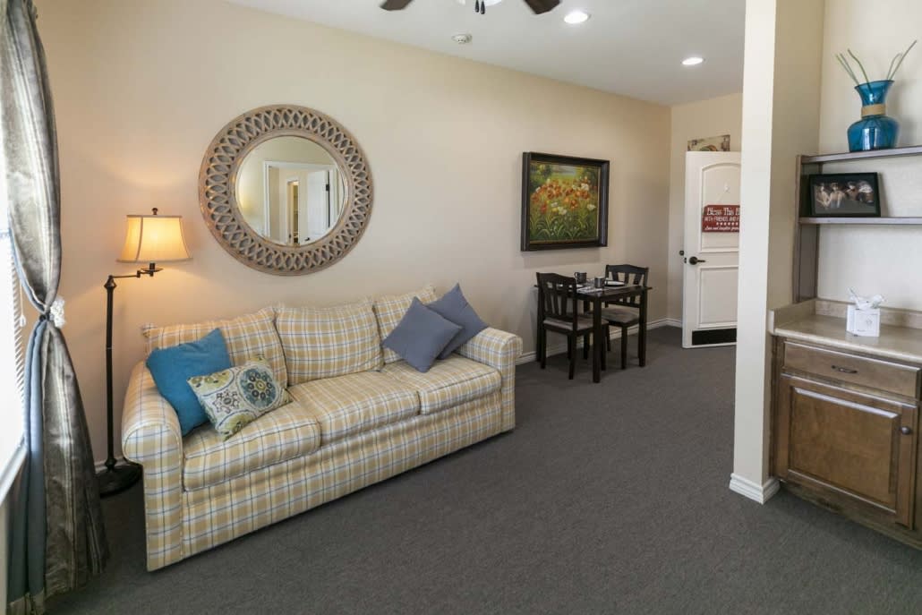 A cozy living room with a striped sofa, decorative mirror, and a small dining area.