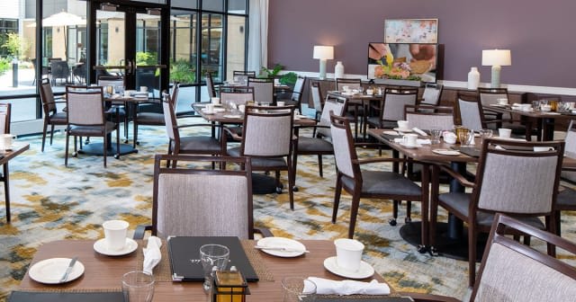 An empty restaurant dining area with neatly set tables and chairs.
