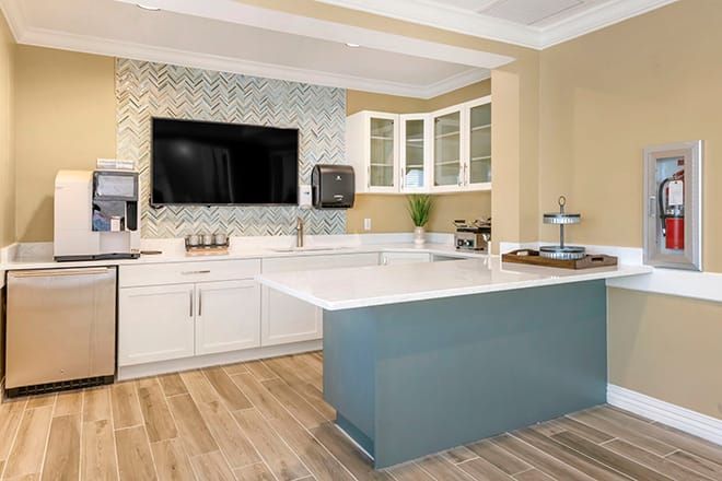 A modern kitchen interior featuring a sleek countertop, contemporary cabinetry, and a wall-mounted television.