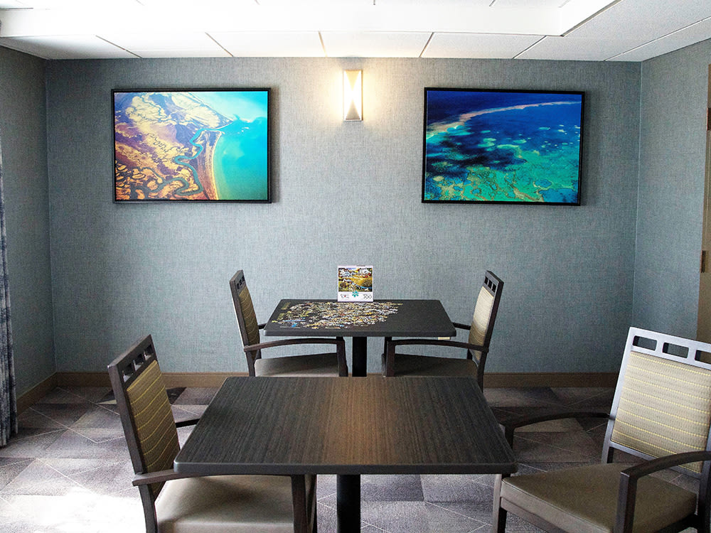 A cozy dining area with two tables, chairs, and vibrant wall art.