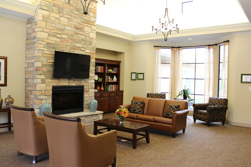A cozy living room featuring a stone fireplace, comfortable seating, and ample natural light.