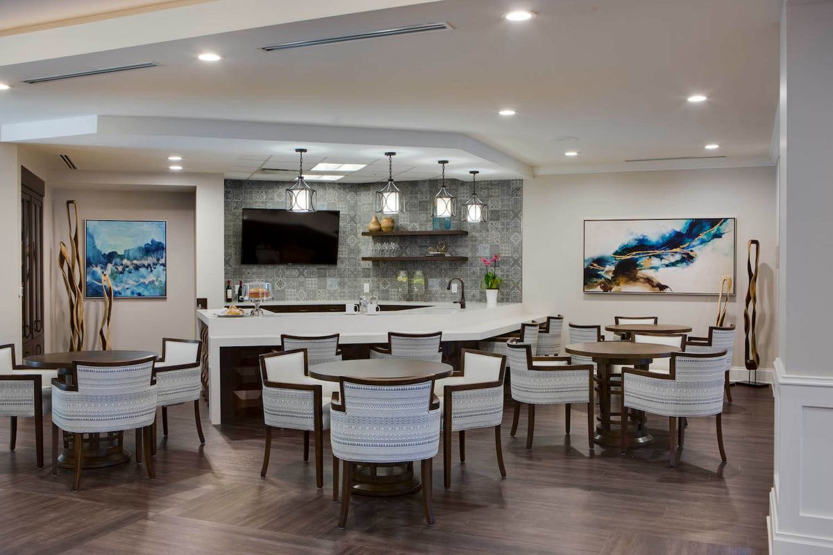 A modern lounge area with a bar counter, seating, and decorative artwork.