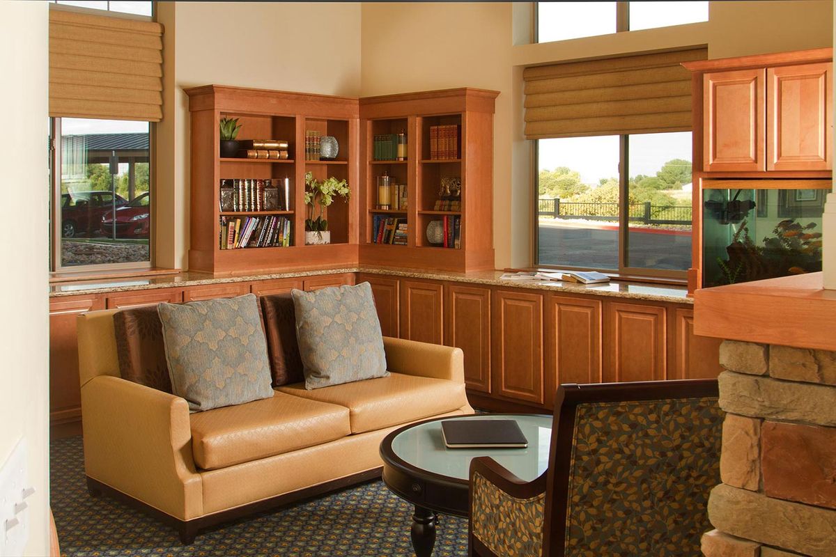 A cozy reading area with a sofa and bookshelves by large windows.