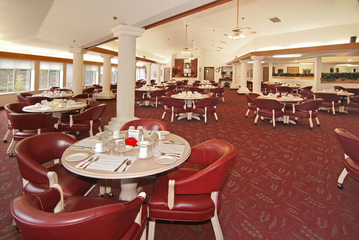 A spacious and elegantly decorated restaurant dining area with red chairs and neatly set tables.