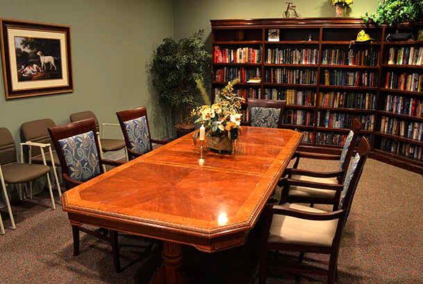 A conference room with a large wooden table and bookshelves filled with books.