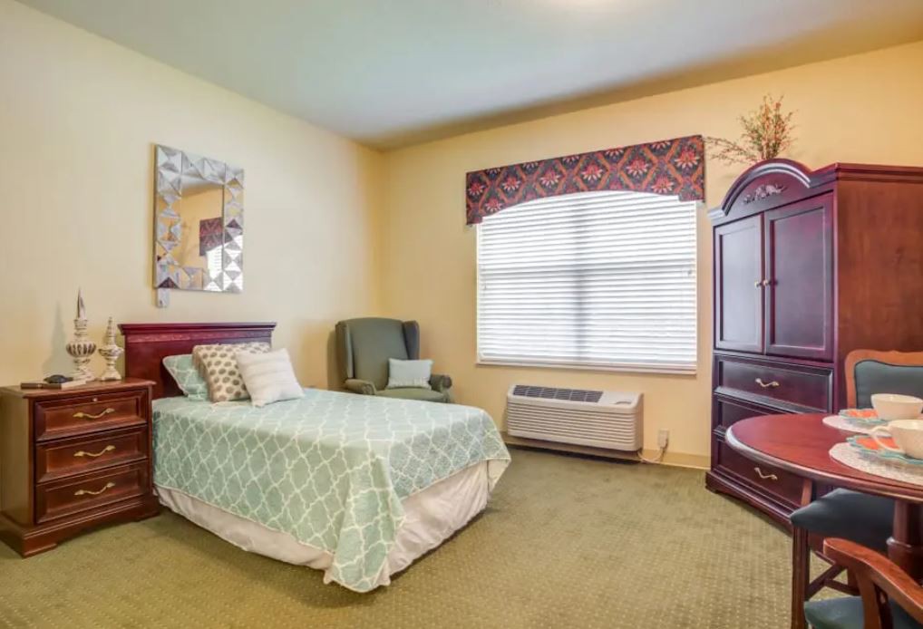 A cozy bedroom with a single bed and armchair near the window.