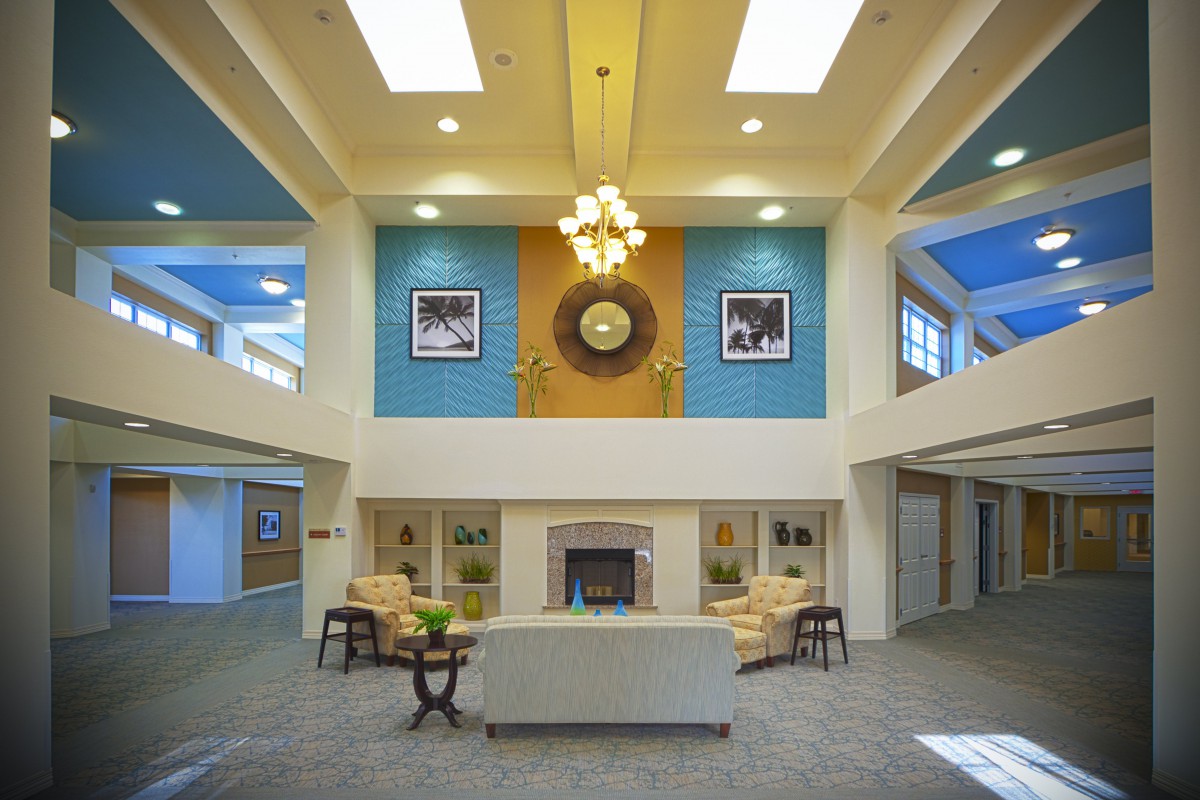 A modern lobby with a central fireplace, elegant chandelier, and comfortable seating area.