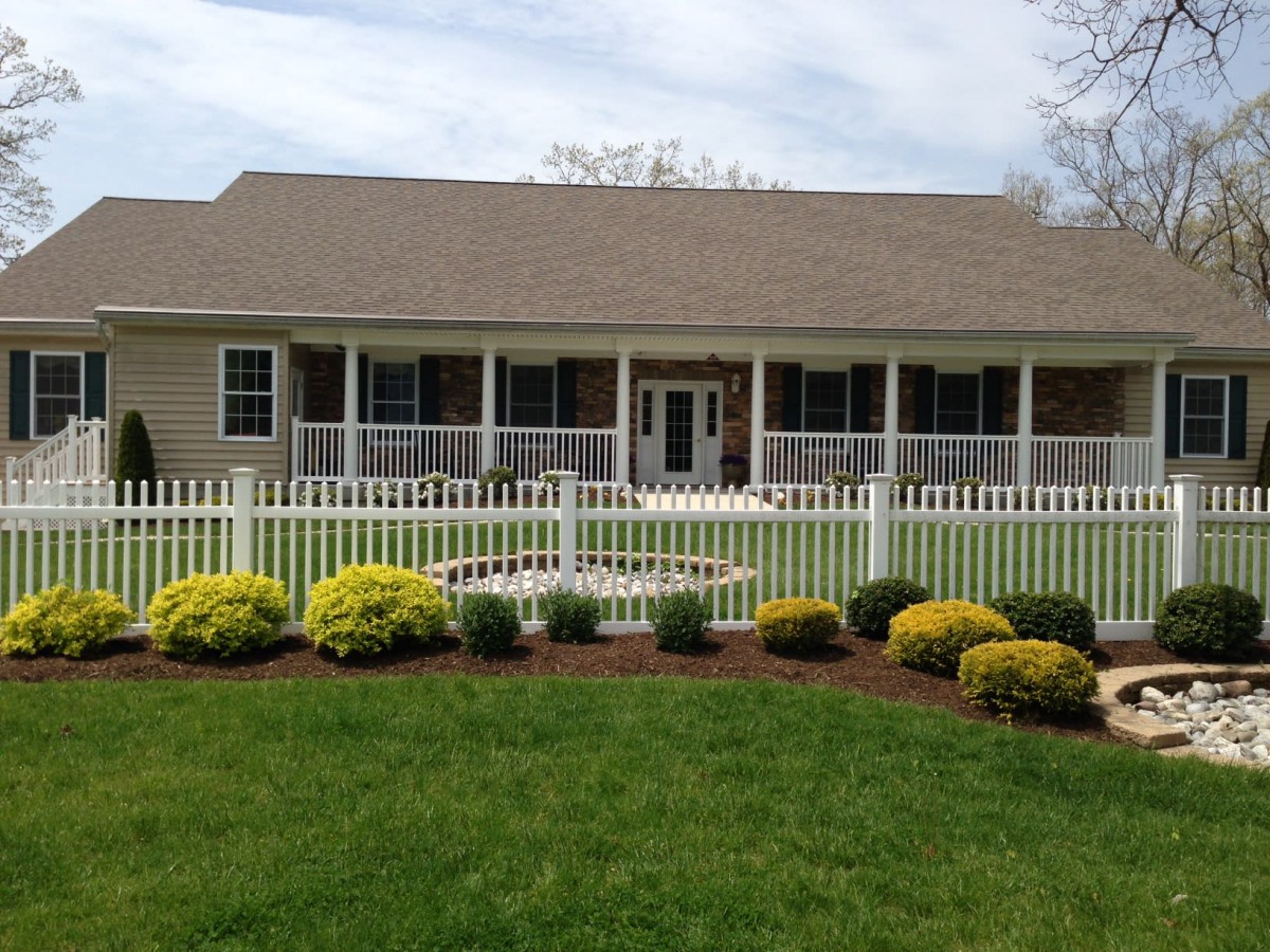 A well-maintained house with a neatly landscaped front yard and a white picket fence.