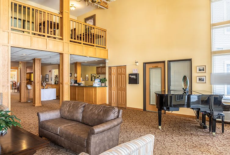 A spacious hotel lobby featuring a comfortable seating area and a grand piano.