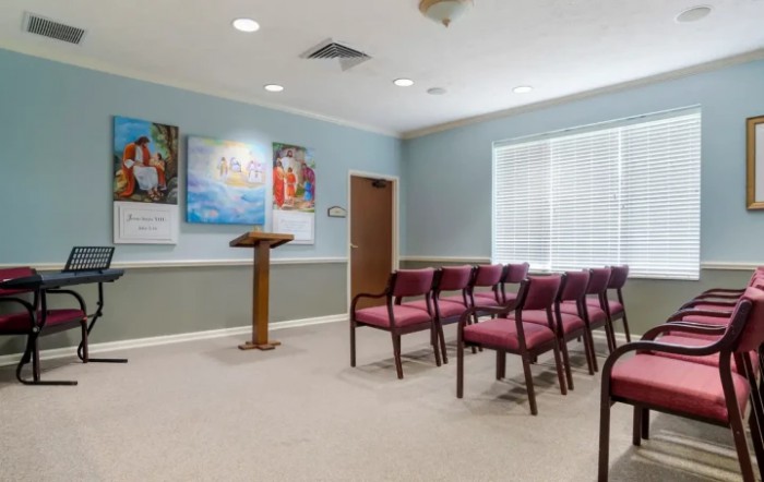 An empty meeting room with rows of chairs and a podium.