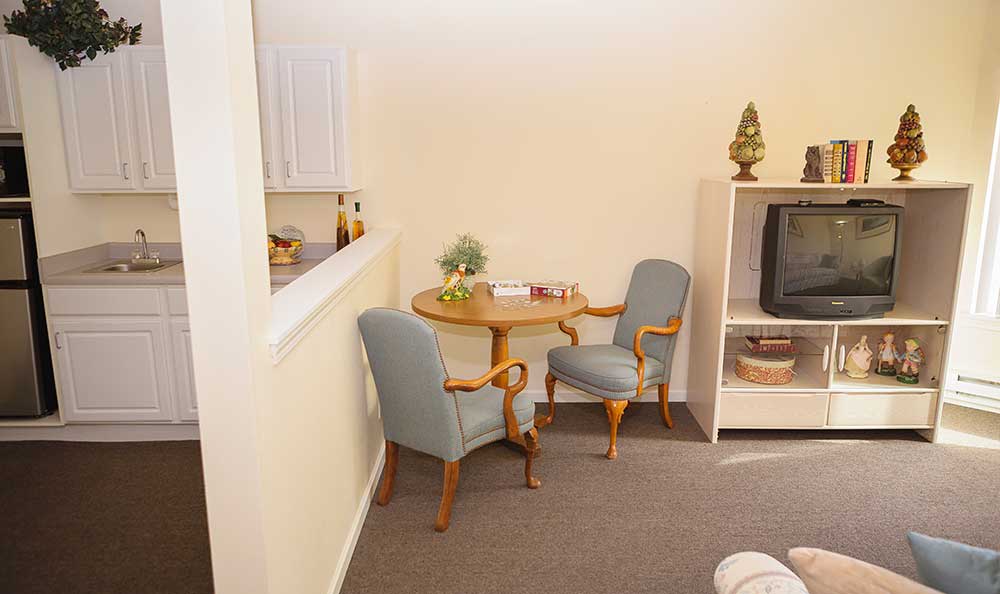 A cozy living room corner with a small table and chairs next to a TV stand.