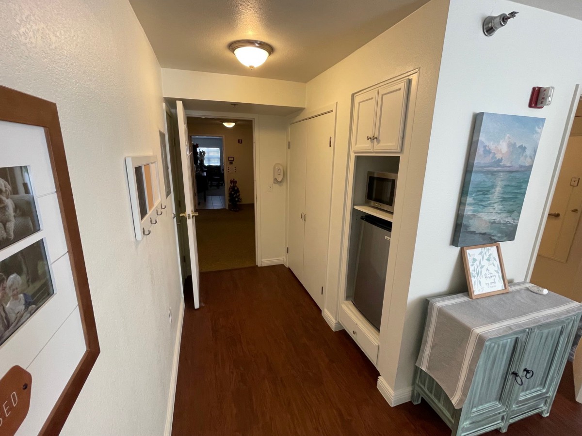 A view of a hallway with hardwood flooring, featuring a door and artwork on the walls.