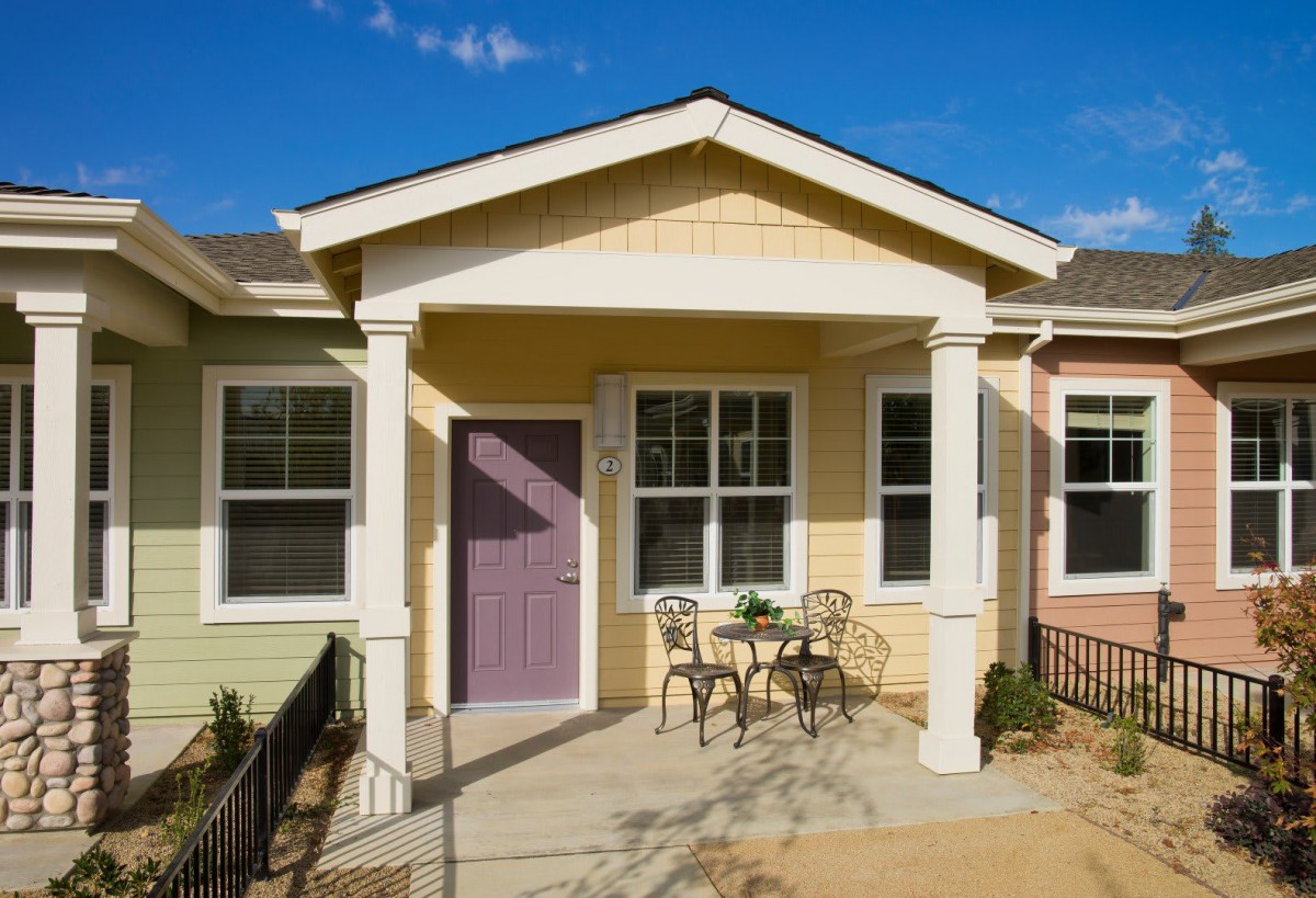 A cozy small house with a front porch and outdoor seating.
