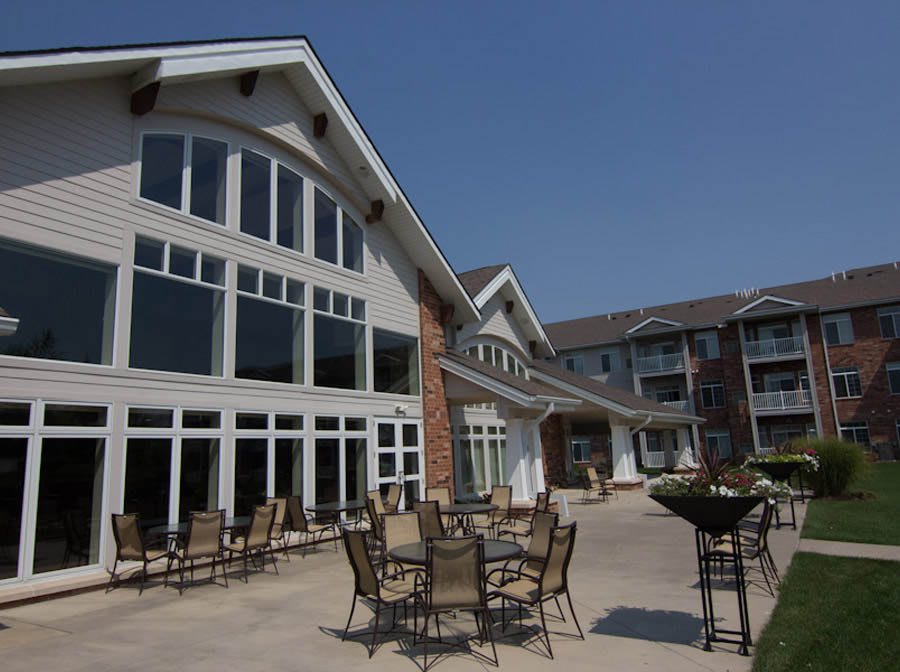 A modern residential building with a spacious patio featuring outdoor seating.