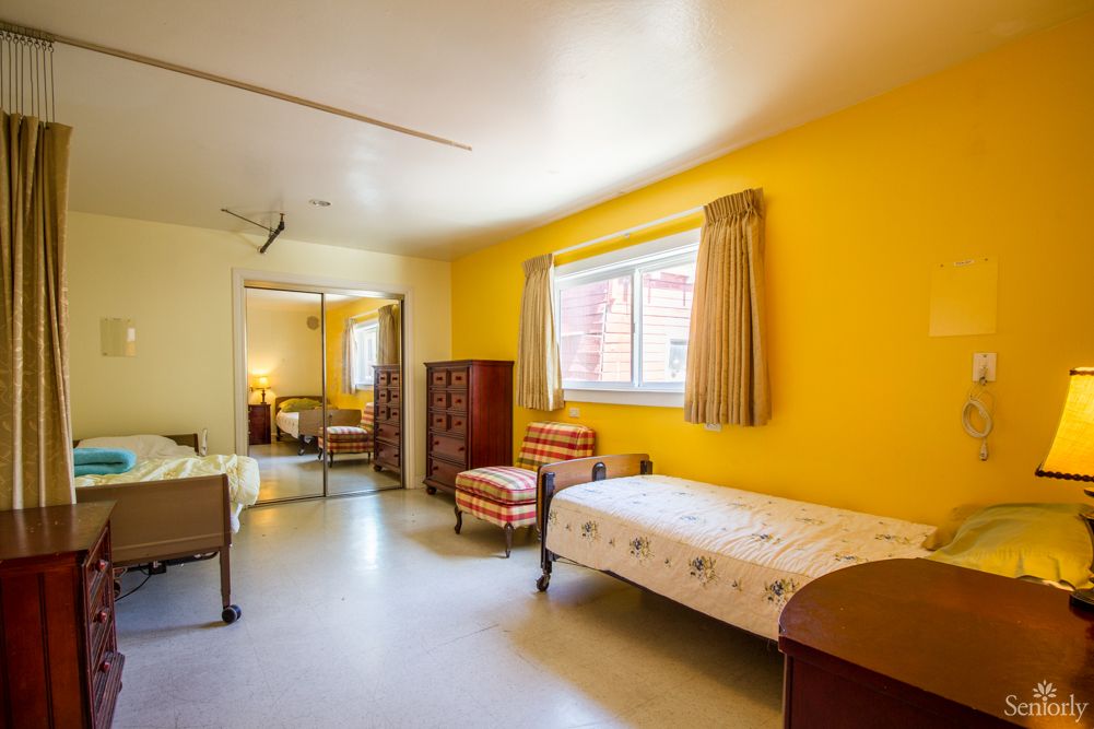 A cozy bedroom with bright yellow walls, featuring a single bed and simple furnishings.