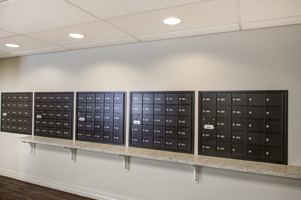 A row of wall-mounted mailboxes in an apartment building hallway.