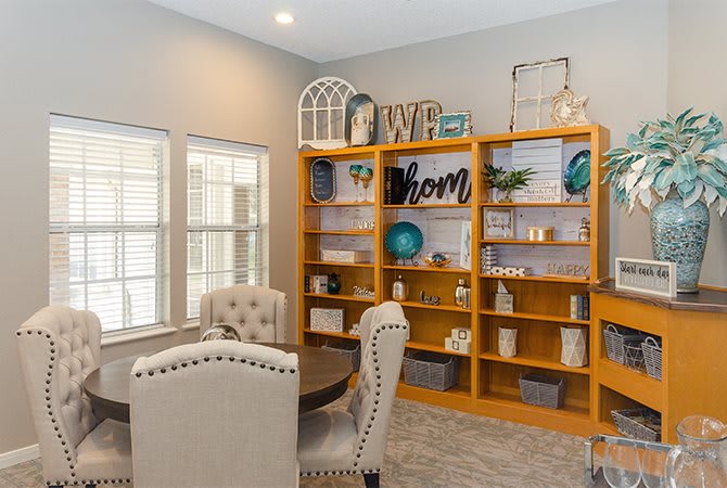 A cozy home office with a wooden bookshelf and upholstered chairs.