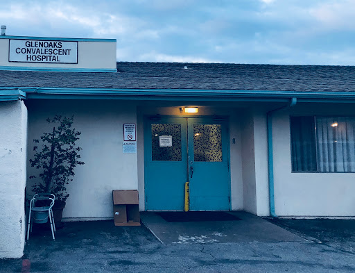 An evening view of a commercial building with teal doors and a welcoming entrance.