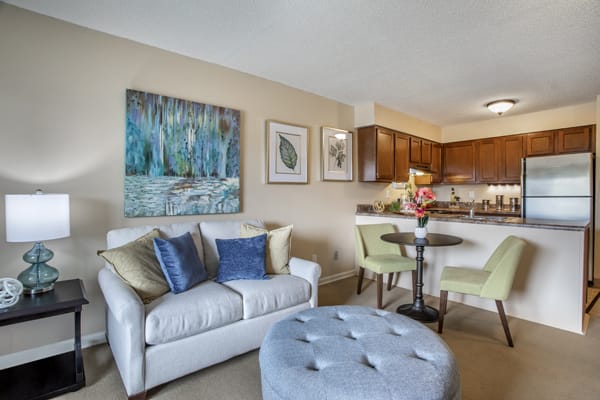 A cozy living room with a sofa, artwork, and an open kitchen area.