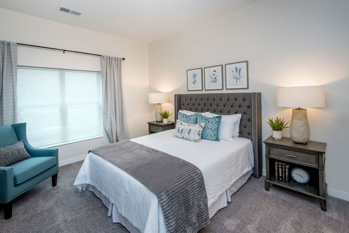 A modern bedroom featuring a neatly made bed with decorative pillows, nightstands with lamps, and framed artwork above the headboard.