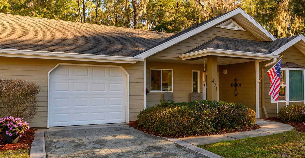 A cozy residential house with a garage and driveway surrounded by trees.