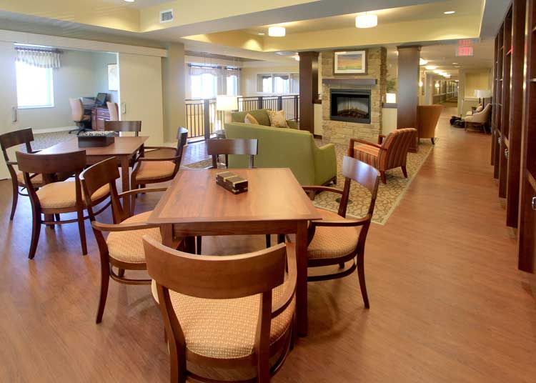 A cozy interior with a dining area featuring wooden tables and chairs, adjacent to a comfortable lounge space.