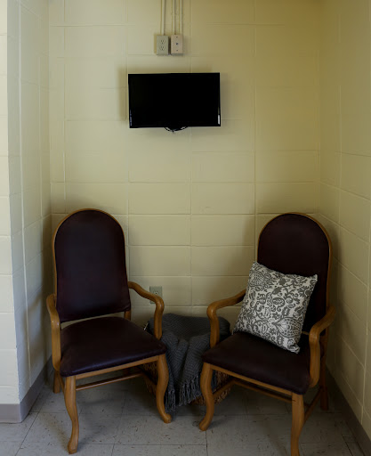 A cozy waiting area featuring two wooden chairs and a wall-mounted TV.