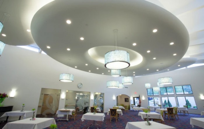 A modern dining area with elegant lighting fixtures and neatly arranged tables and chairs.