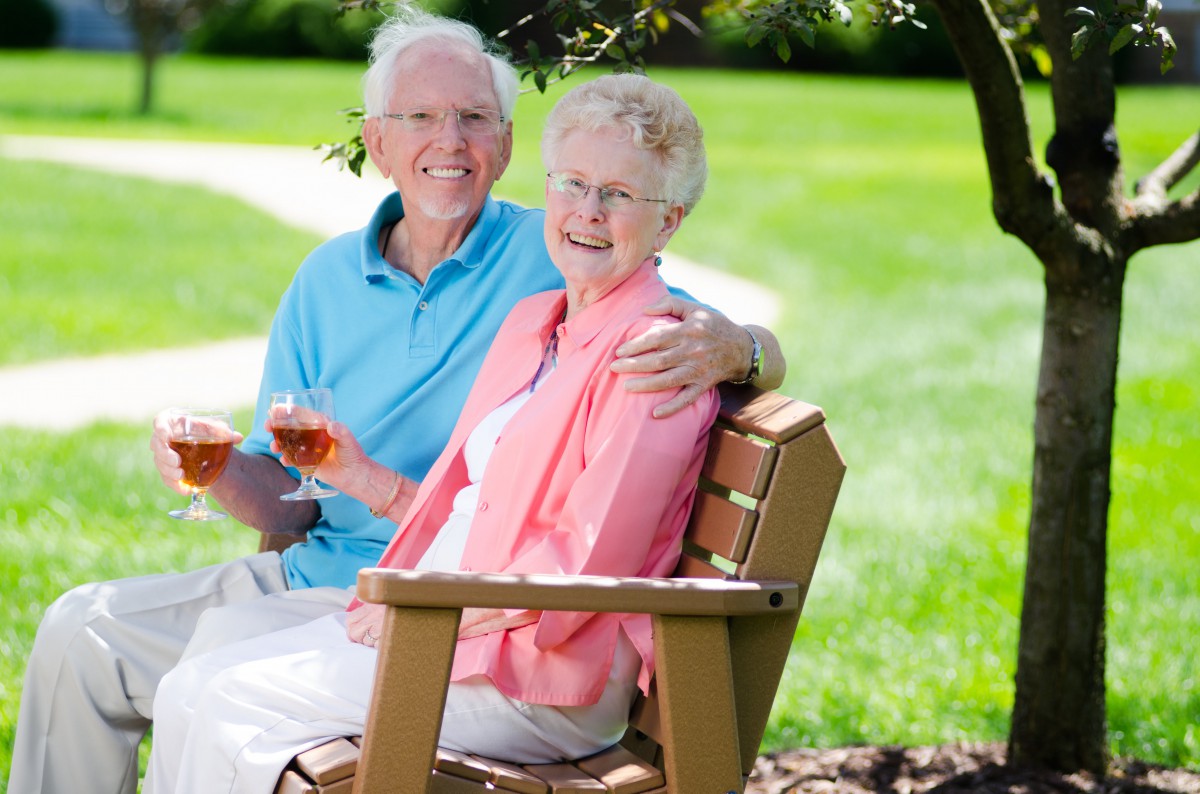 An elderly couple enjoying a sunny day in the park, sitting together on a bench.