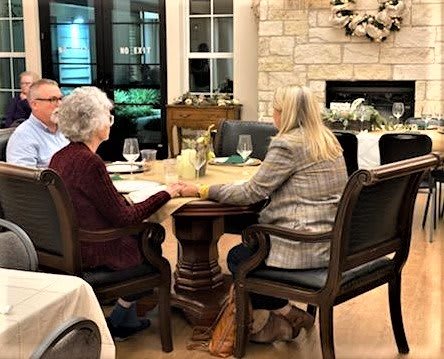 A group of people sharing a meal and conversation in a cozy dining room.