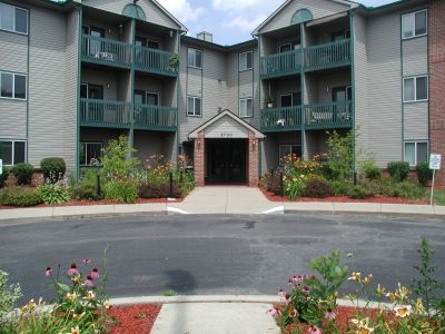 A residential apartment building with balconies and a landscaped entrance.