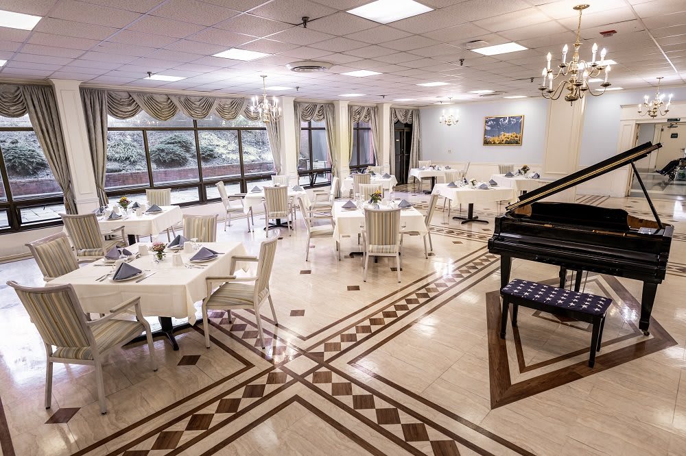 An elegant dining area with neatly arranged tables and a piano.