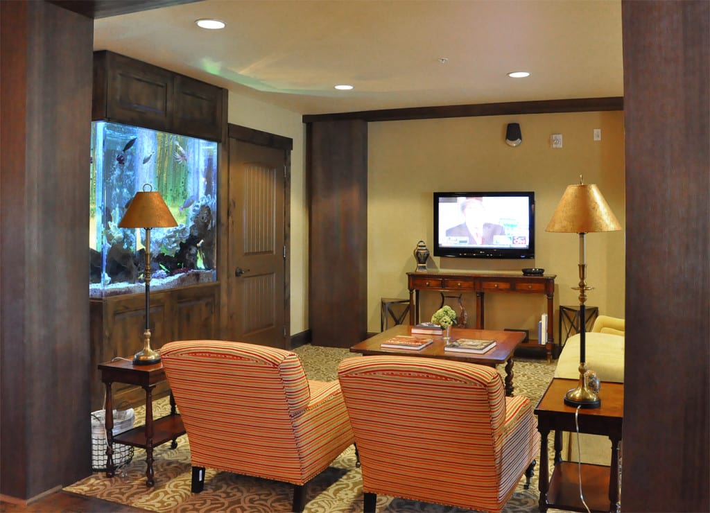 A cozy living room featuring an aquarium and a television with comfortable seating.