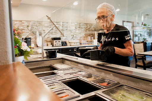 An elderly worker prepares ingredients at a food counter, showcasing dedication and experience in the culinary field.