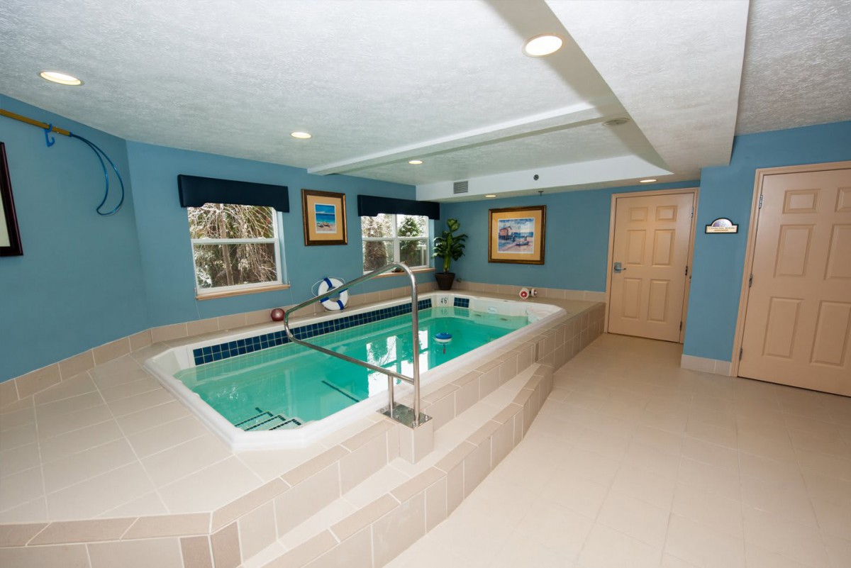 A cozy indoor swimming pool designed for exercise and aquatic therapy, featuring blue walls and well-lit surroundings.