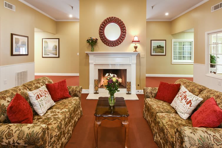 A cozy living room with a traditional fireplace and floral decor.