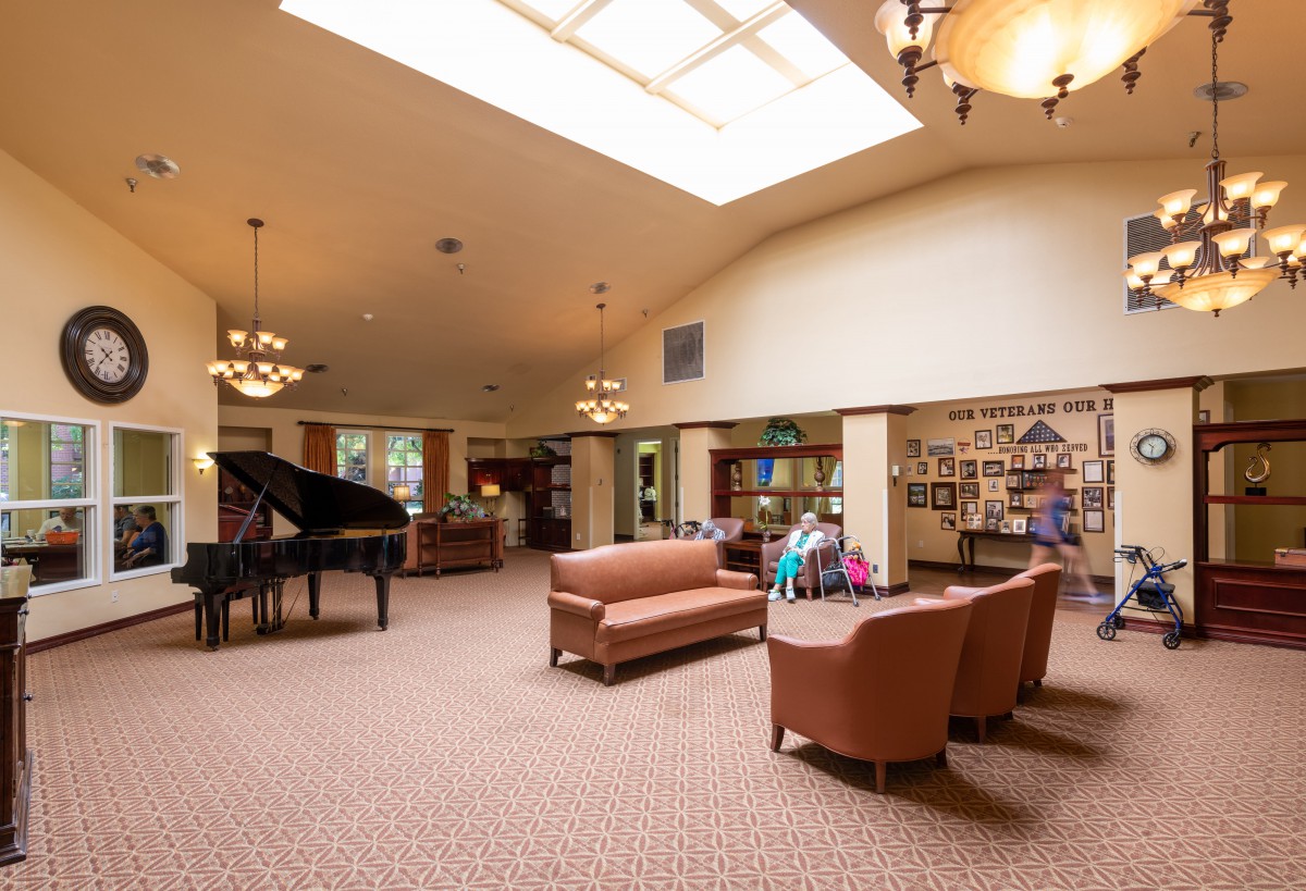 A spacious and comfortable lounge area featuring a grand piano, seating arrangements, and warm lighting.