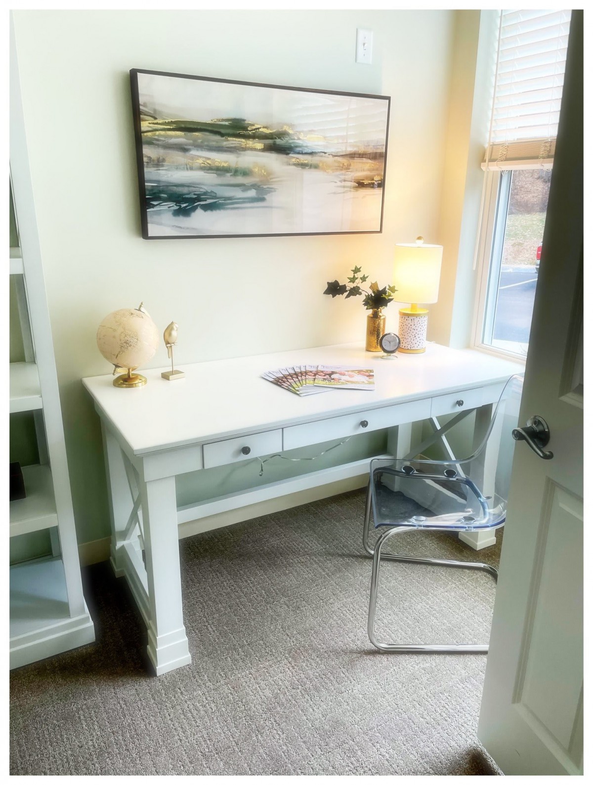 A bright and minimalist home office setup featuring a white desk, modern chair, and decorative elements.