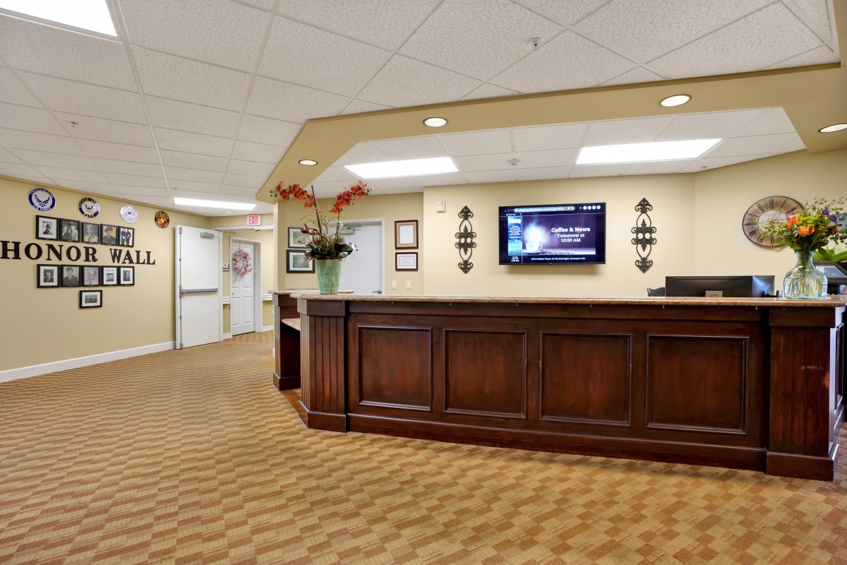 A well-lit reception area with a wooden desk and a television mounted on the wall.