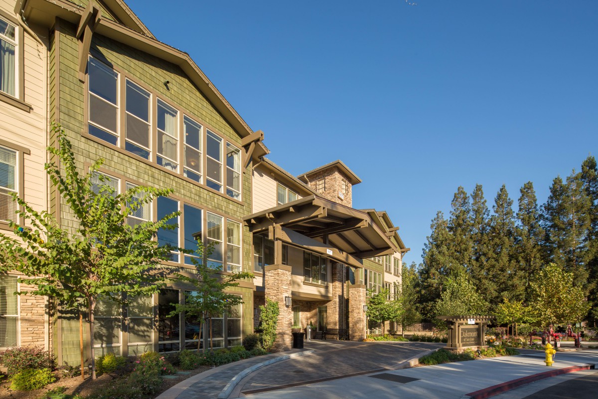 A modern residential building with a scenic exterior and trees surrounding the entrance.