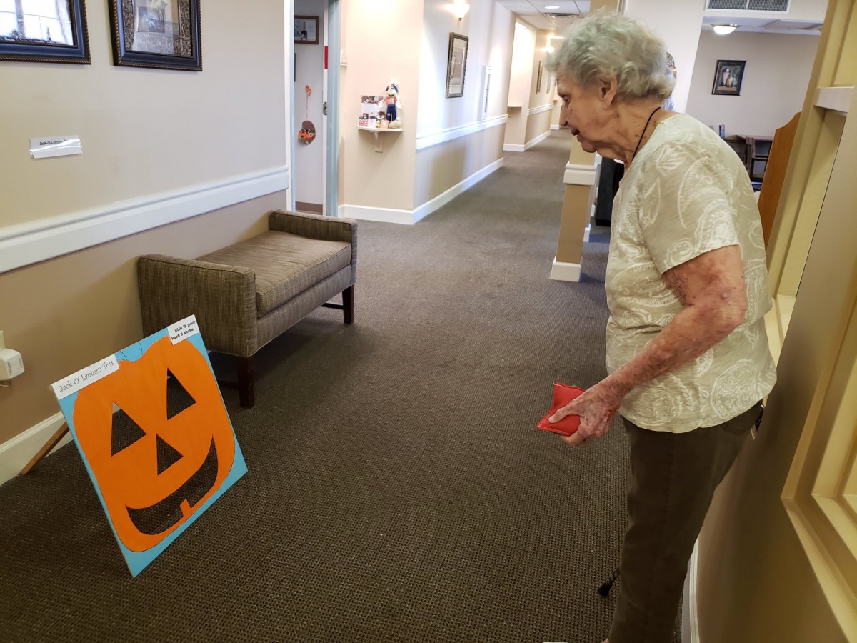 An elderly woman playing a Halloween-themed game indoors.