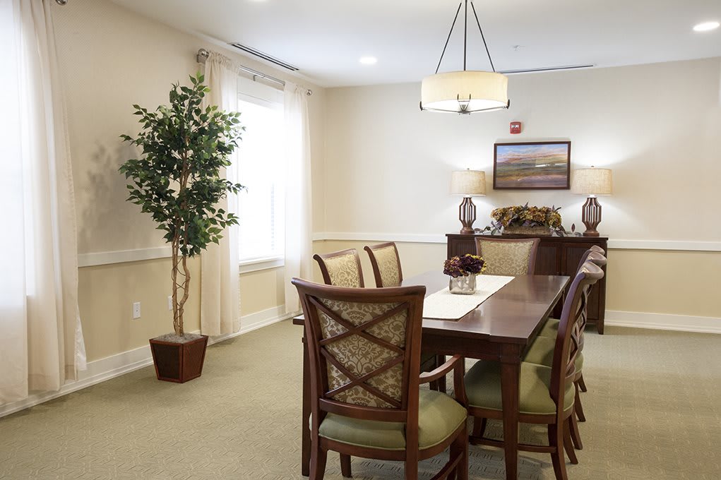 A well-lit dining room with a wooden table, chairs, a potted plant, and wall decor.