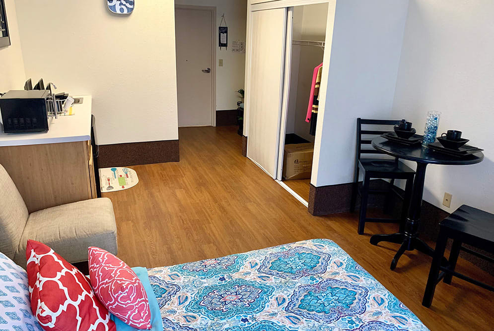 A cozy living space with a bed, wardrobe, and wooden flooring.