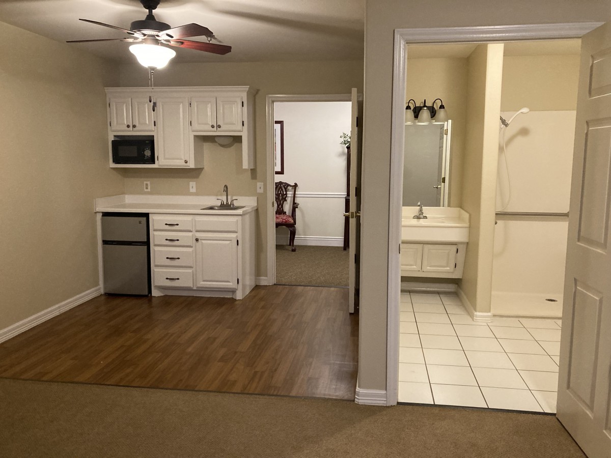An interior view of an apartment with a small kitchen and adjacent bathroom.